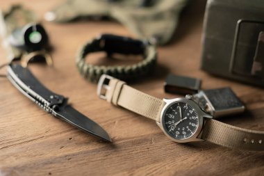 Biege naylon saat bandıyla askeri kol saatini kapat. Arka planda askeri nesneler olan erkekler için kol saati.