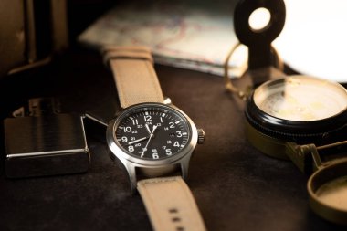 Biege naylon saat bandıyla askeri kol saatini kapat. Arka planda askeri nesneler olan erkekler için kol saati.