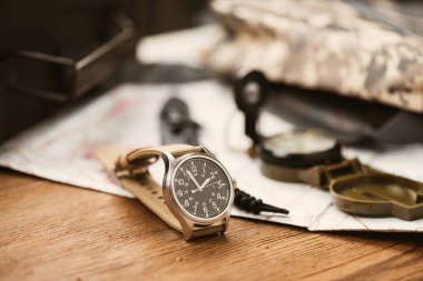 Biege naylon saat bandıyla askeri kol saatini kapat. Arka planda askeri nesneler olan erkekler için kol saati.