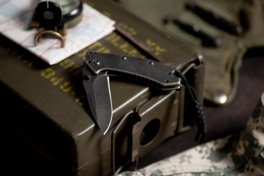 Paslanmaz çelik çakı ve arkasında askeri nesneler var..