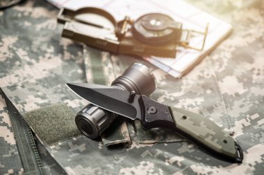 Paslanmaz çelik çakı ve arkasında askeri nesneler var..