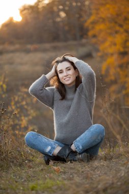 Güzel, mutlu, genç bir kadın akşam vakti dışarıda oturuyor. Sonbahar