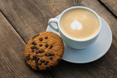 Kapuçino ve kurabiye ahşap bir masada..