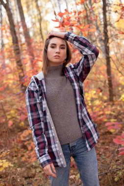 sonbahar ormanda yürüyen genç bir kadın.