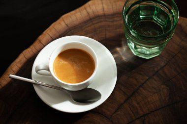 Beyaz bardakta bir bardak suyla servis edilen Espresso.