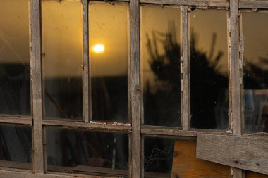 Eski bir evin penceresinde gün batımının yansıması.