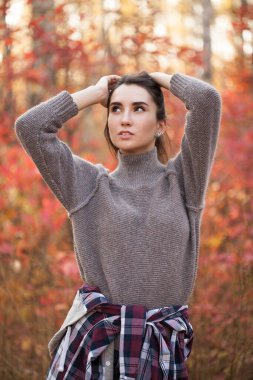 Güz ormanında poz veren çekici genç bir kadın.