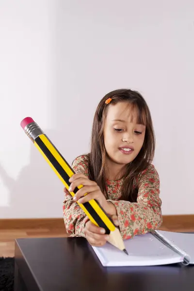 巨大な鉛筆で彼女の家の書き込みで女の子 — ストック写真