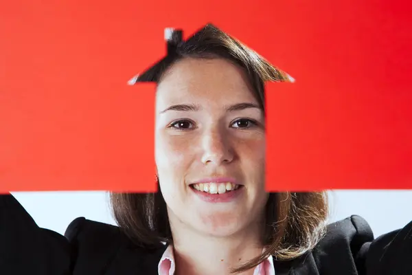 Woman face behind a red cut out paper with a house shape