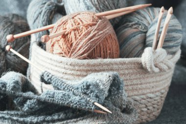 Örgü örme devam ediyor. Yün iplikleri ve sepetteki ahşap örgü iğneleri..