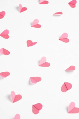 Pink hearts cut out from white paper. Festive background for valentine's day.