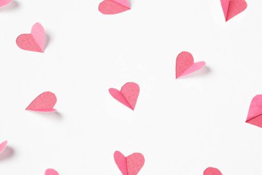 Pink hearts cut out from white paper. Festive background for valentine's day.