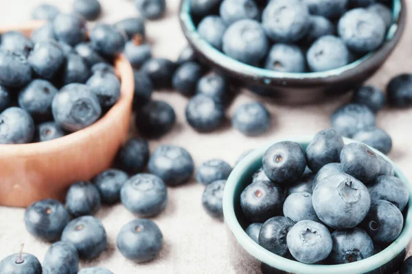 Three ceramic bowls with blueberries and berries scattered around.