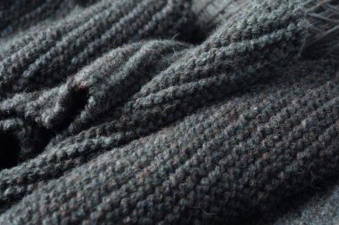 Knitted scarf folds, black and gray stripes. Dark knitted texture background.