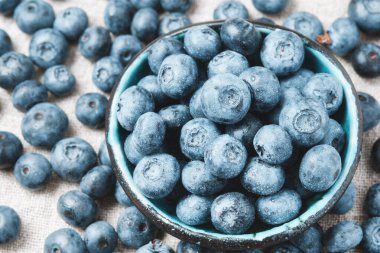 Blueberries with water drops in a ceramic bowl and scattered around.