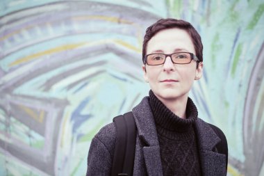 Kısa saçlı gözlüklü kadın portresi. Androgynous görünümü, ikili olmayan kişiliği.