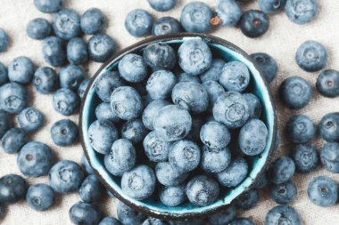 Blueberries with water drops in a ceramic bowl and scattered around.