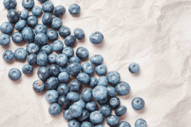 Fresh blueberries scattered on beige craft paper.