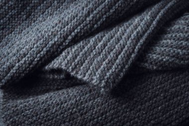 Knitted scarf folds, black and gray stripes. Dark knitted texture background.