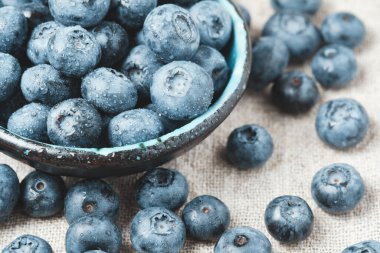 Blueberries with water drops in a ceramic bowl and scattered around.