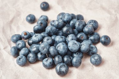 Fresh blueberries scattered on beige craft paper.