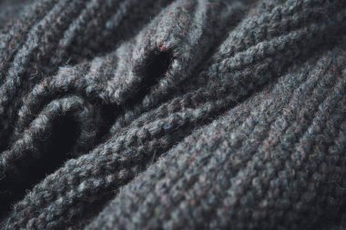 Knitted scarf folds, black and gray stripes. Dark knitted texture background.