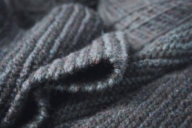 Knitted scarf folds, black and gray stripes. Dark knitted texture background.