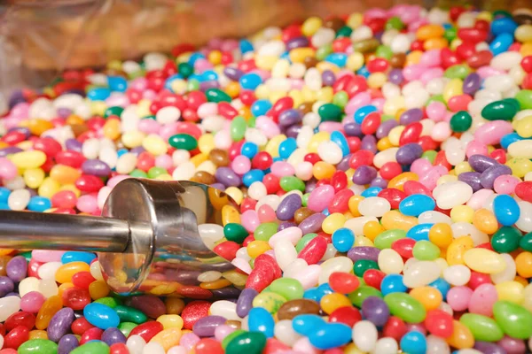 混合的多色果冻豆和一个金属勺在糖果店里 — 图库照片