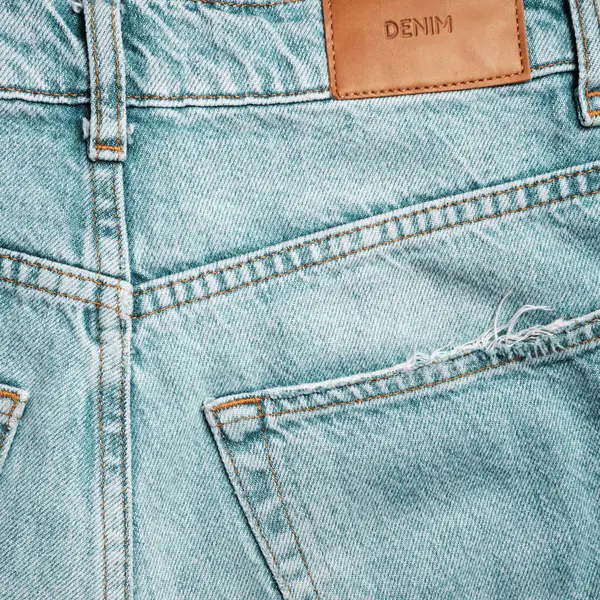 Back of blue jeans close up. Label with the inscription DENIM Fashionable casual wear.