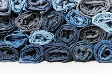 Bir sürü sarılmış kot pantolon. Denim geçmişi. Giysiler, alışveriş, moda, tüketim.