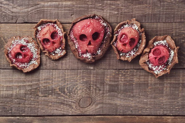 Halloween food. Homemade pie and tartlets with jam and scary skull-shaped pears. Grim Reaper Halloween desserts