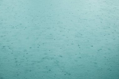 Arkaplan su yüzeyinde yağmur damlaları var. Su dalgalanması dokusu.