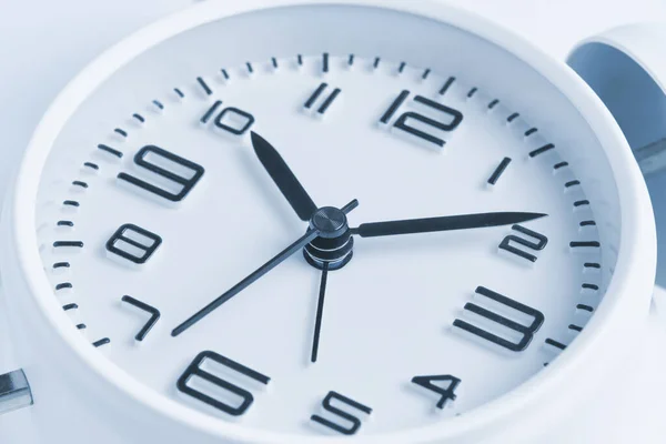 Close-up of a white alarm clock, ten o'clock.