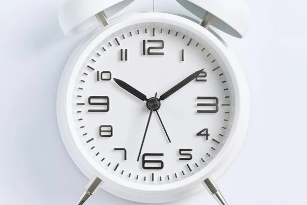 Close-up of a white alarm clock on a white background, ten o\'clock.
