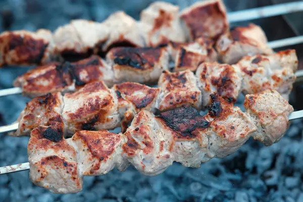 Cooking barbecue pork meat on smoking coals. Shish kebab on the grill.