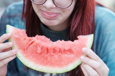 Bir dilim olgun kırmızı karpuz yiyen kız, yakın plan..