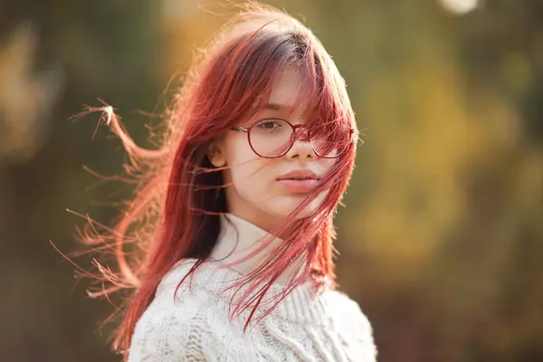 Beautiful teenage girl with hair blowing in the wind. Autumn colors.