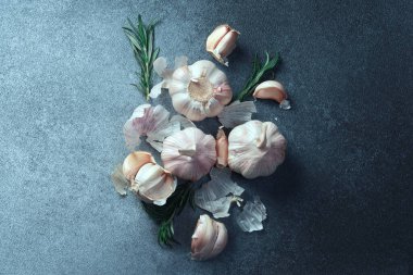 Dokulu yüzeyde sarımsak ve biberiye. Taze sarımsak soğanları ve biberiyeli karanfiller desenli gri bir yüzeye saçılmış..