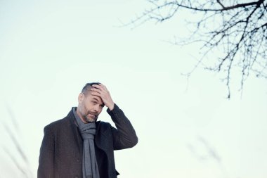 Mavi ceketli orta yaşlı bir adamın portresi ve alnında yün bir eşarp..