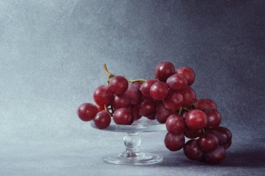 Gri desenli bir arka plana karşı Temiz Cam bir yaylada Taze Kırmızı Üzüm Demeti
