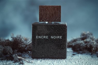 KYIV, UKRAINE - JULY 31, 2024. Encre Noire Lalique perfume bottle covered in droplets of water, cool and moody atmosphere. clipart