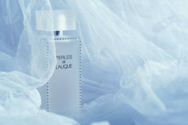 KYIV, UKRAINE - 30 Temmuz 2024. Perles de Lalique parfüm şişesi. Buzlu cam tasarımı. Etrafı yumuşak beyaz kumaşlarla çevrili.