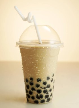 Plastik bardakta buzlu çay ve saman.