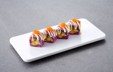 Siyah tabakta krem ve peynirli lezzetli suşi ruloları.