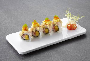 Siyah taş arka planda somonlu suşi ruloları.