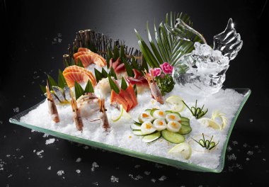 Siyah bir tabakta taze sashimi ve deniz ürünleri..