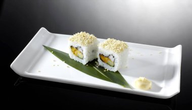 Soya sosu ve susam tohumlu siyah tabakta lezzetli suşi ruloları.