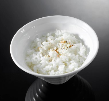 Siyah arka planda beyaz kasede pirinç.