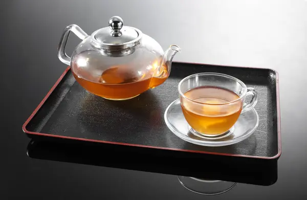 tea ceremony, teapot and glass of red tea on black background