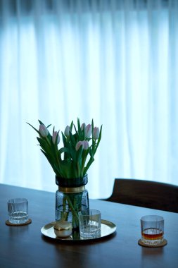 Bir bardak kahve ve çiçekler ahşap masada.